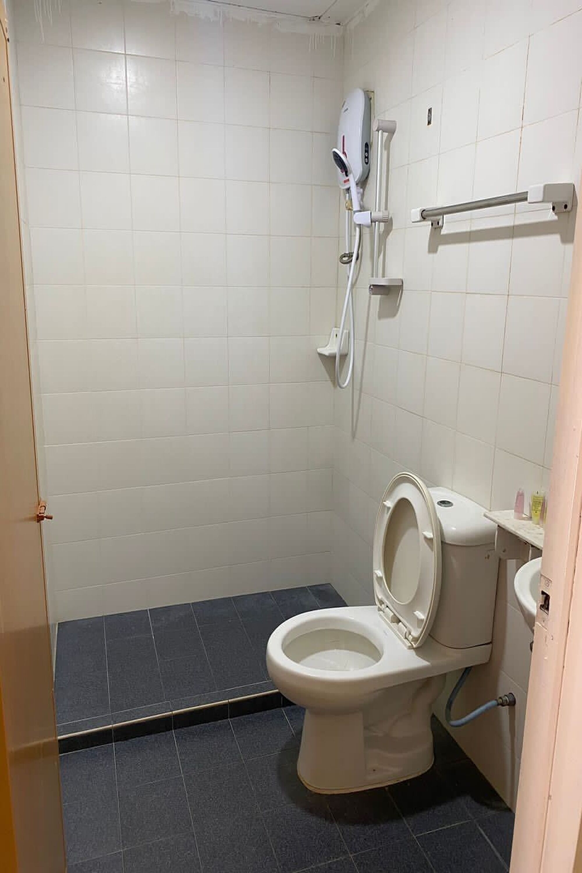 A small, clean bathroom with a toilet, a shower area, and a hand dryer.