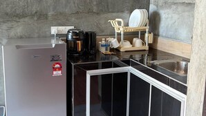 A compact kitchen with a built-in refrigerator, a coffee maker, and a dish rack. - Corrie Chalet Pantai Cenang Langkawi (Langkawi)