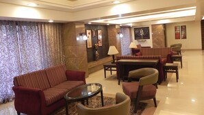 A spacious lobby with a sofa, armchairs, a coffee table, and a dining area. - Hotel Reeva Suites (Rahata)
