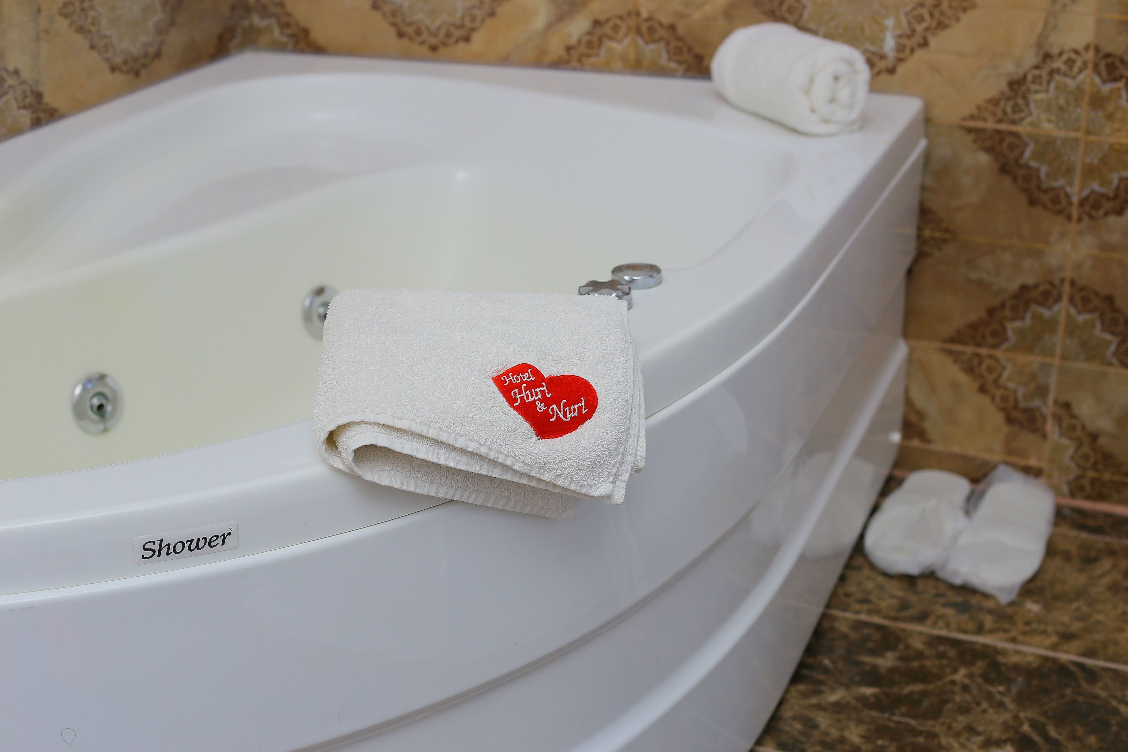 A white bathtub with a towel featuring a heart-shaped logo and the text "Hotel Hunt & Nuri."