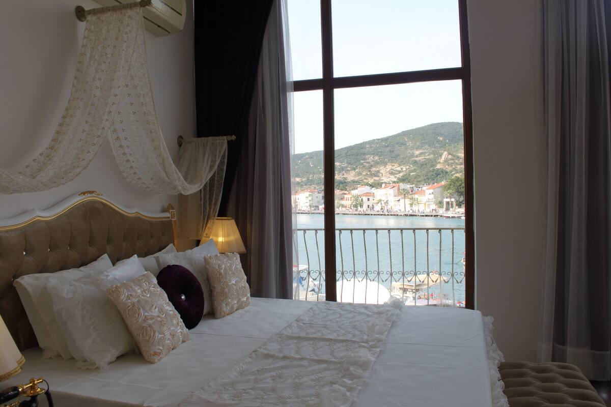A bedroom with a large bed, a view of a body of water, and a balcony.