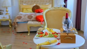 A neatly arranged breakfast table with a wine bottle, fruit, and a box, in a room with a bed and a nightstand. - Huri & Nuri Hotel (Foça)