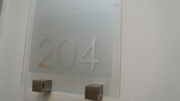 A number '204' on a frosted glass door, with two small, square, brown objects attached to the glass.