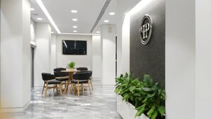 Une salle de conférence moderne avec un sol en marbre, une table ronde et six chaises. Un grand écran est fixé au mur, et un logo est affiché sur le mur, à droite.