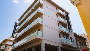 Un hôtel à plusieurs étages, doté d’une architecture moderne, avec des balcons à chaque étage et une enseigne bien visible indiquant qu’il s’agit de l’hôtel Piraeus Port.