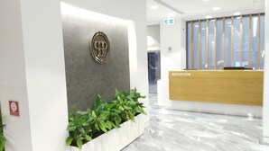 Un espace d’accueil doté d’un sol en marbre, d’un comptoir de réception portant l’inscription « RÉCEPTION » et d’un logo sur le mur.