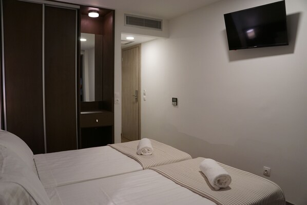 A hotel room with a bed, a television mounted on the wall, and a door leading to a bathroom. - Piraeus Port Hotel (Piraeus)