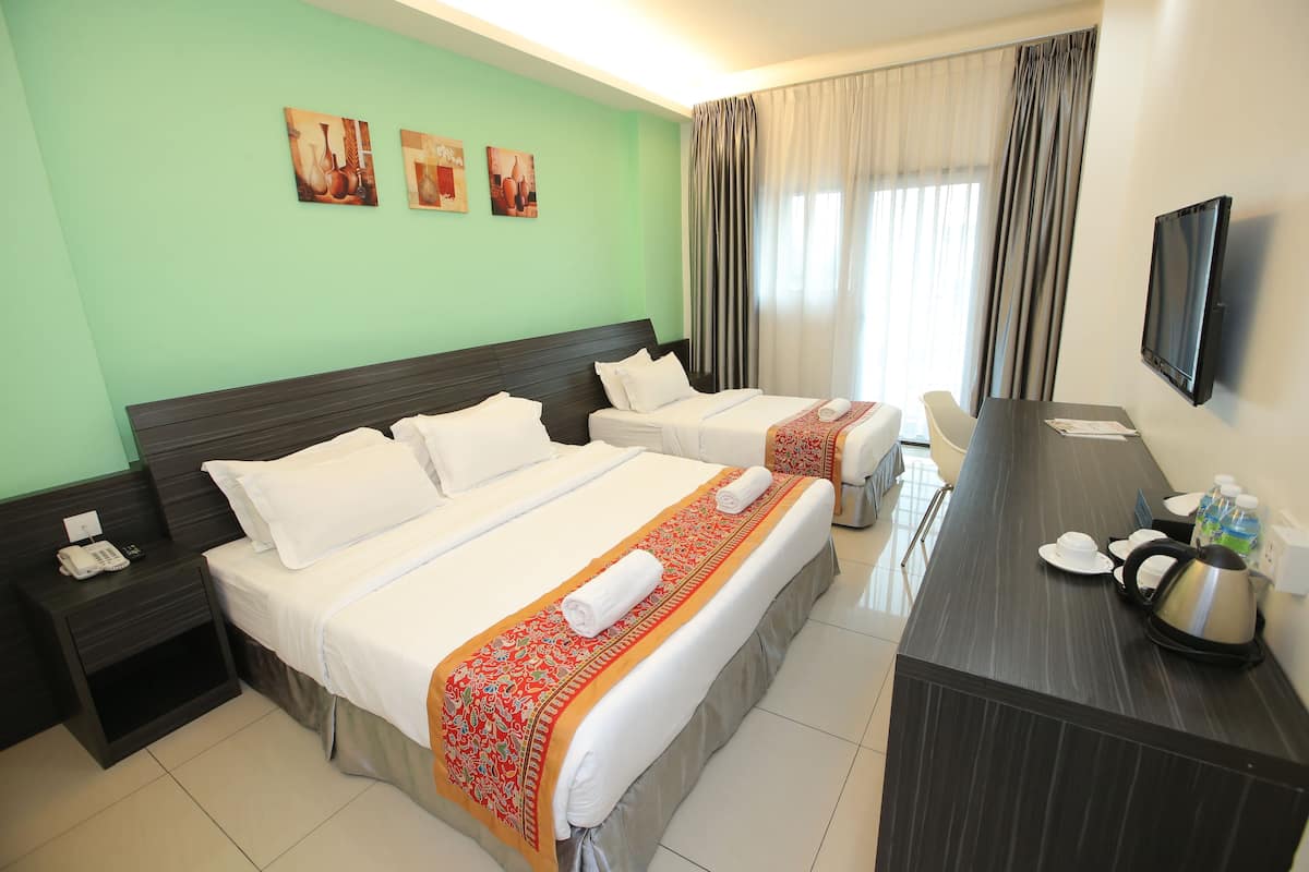 Ein Hotelzimmer mit zwei Betten, einem Schreibtisch mit Wasserkocher, Telefon und Fernseher.