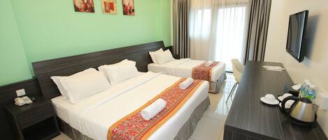A hotel room with two beds, a desk with a kettle, a phone, and a TV.