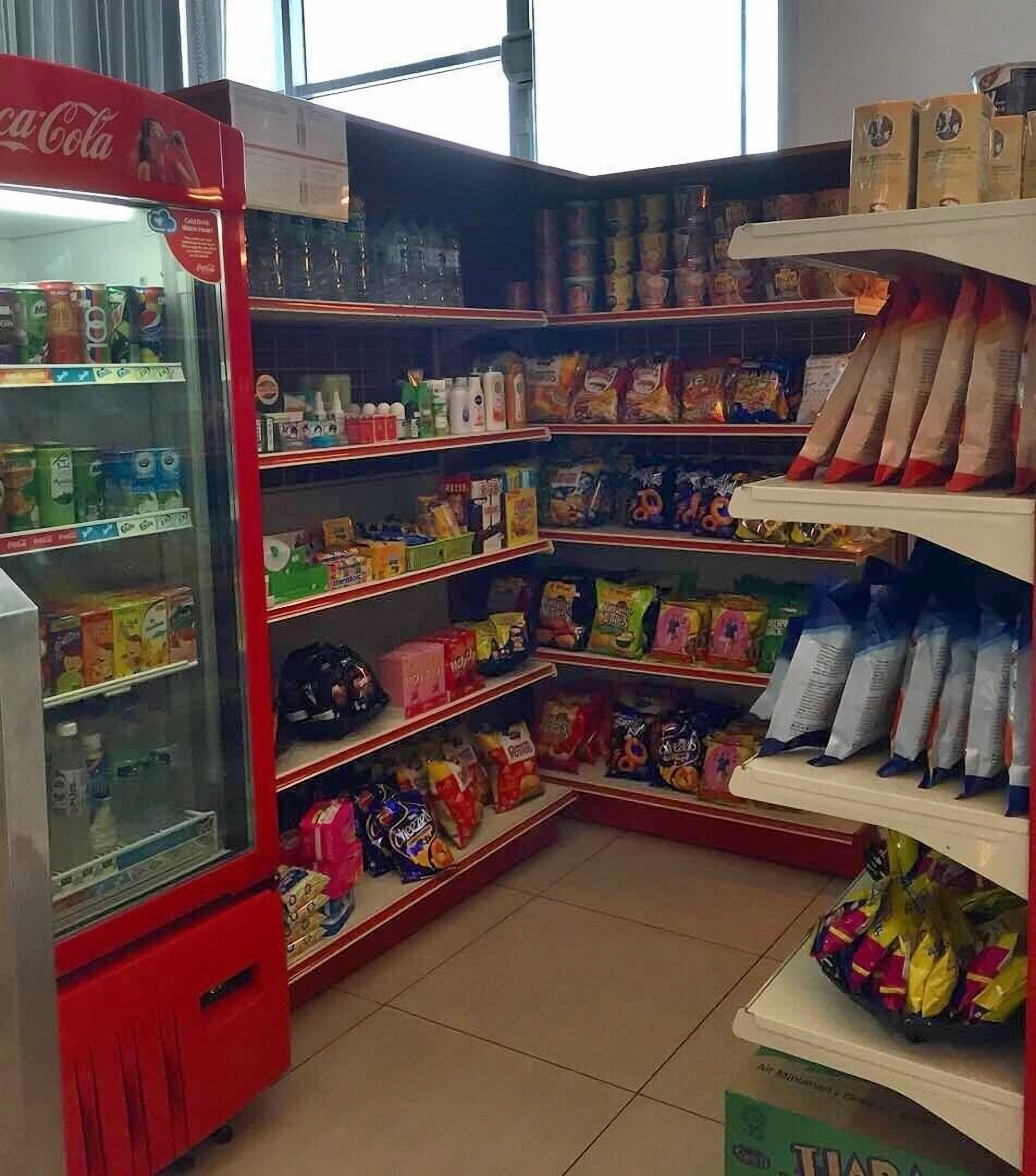 Un supermercado con estantes llenos de aperitivos, bebidas y artículos para el hogar.