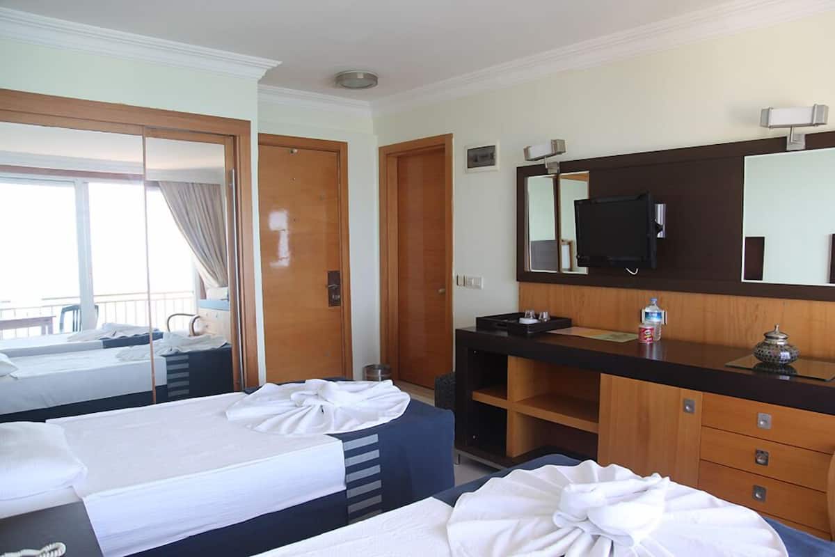 A hotel room with two beds, a large mirror, a TV, and a minibar.
