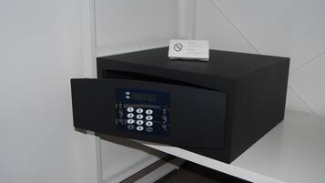 Una caja fuerte negra con teclado y ranura para tarjeta sobre un estante blanco.