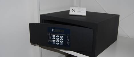 A black safe with a keypad and a card slot on a white shelf.