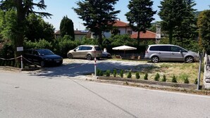 A parking area with several cars, a white umbrella, and a stone wall.