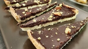 A dessert with a chocolate layer and nuts on a plate.