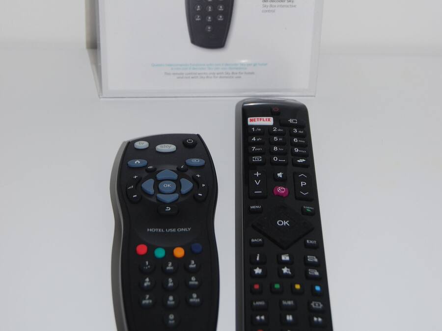 A Sky remote control box and two remote controls, one labeled 'HOTEL USE ONLY' and the other 'HITACHI'.