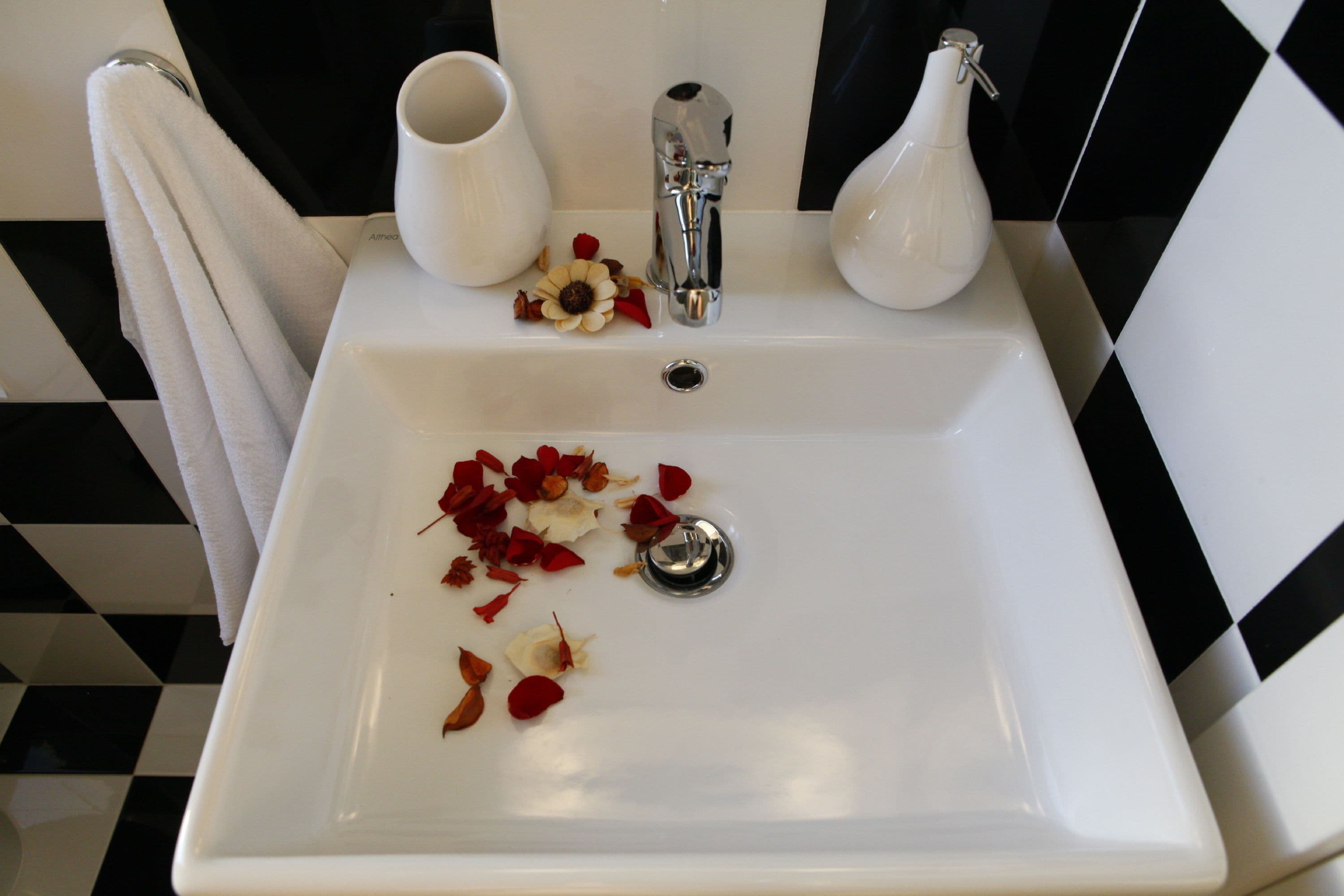 A bathroom sink with a white countertop, a faucet, and a vase.