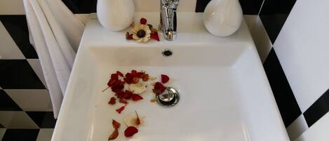A bathroom sink with a white countertop, a faucet, and a vase.