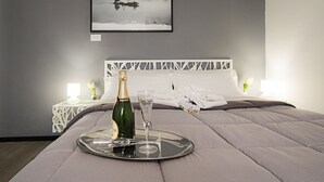 A neatly made bed with a tray holding a bottle and a glass, a framed picture on the wall, and a white headboard. - City Lights Rome (Rome)