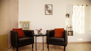 A room with two black leather sofas, a small table with cups and a vase, a radiator, a framed picture on the wall, and a mirror with a wavy design. - City Lights Rome (Rome)