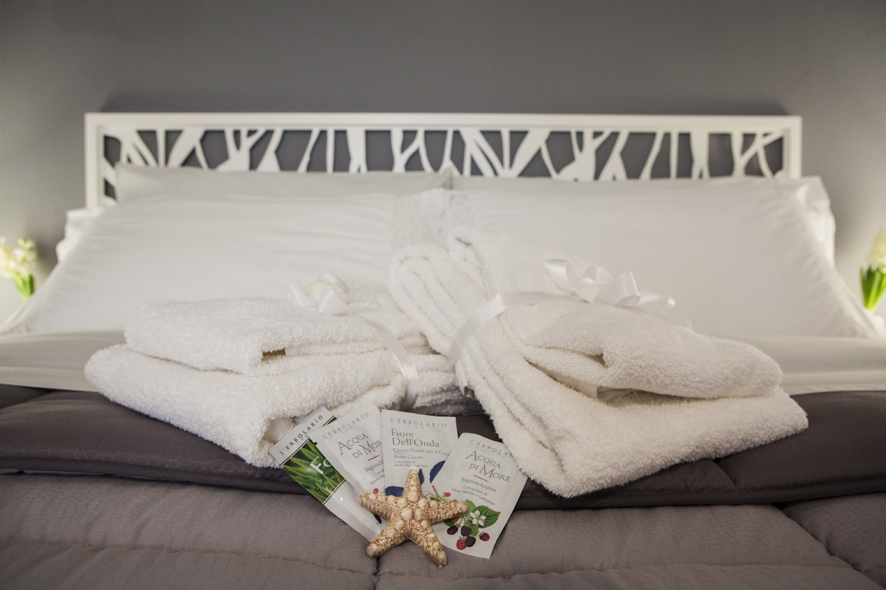 A bed with white linens, a starfish decoration, and brochures on the pillows.