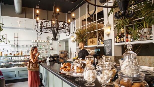 A café with a counter displaying pastries and a bar area with bottles. - City Lights Rome (Rome)