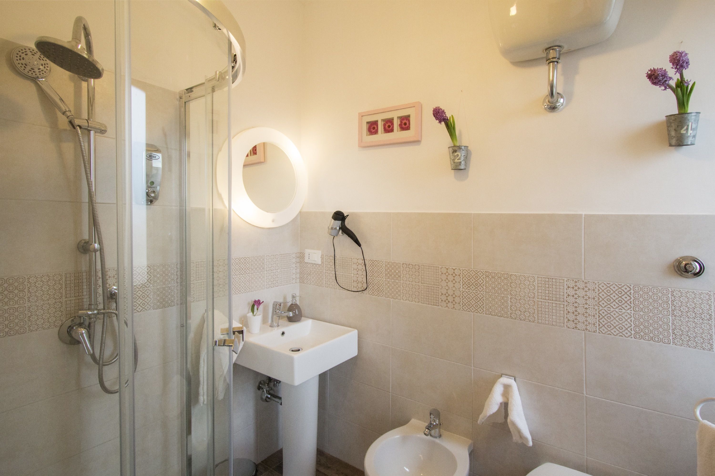 A bathroom with a glass-enclosed shower, a sink, a bidet, and a toilet.