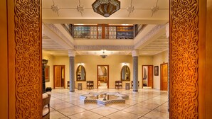 Un lobby amplio con una fuente central, elaboradas esculturas de madera y un nivel intermedio con balcón.