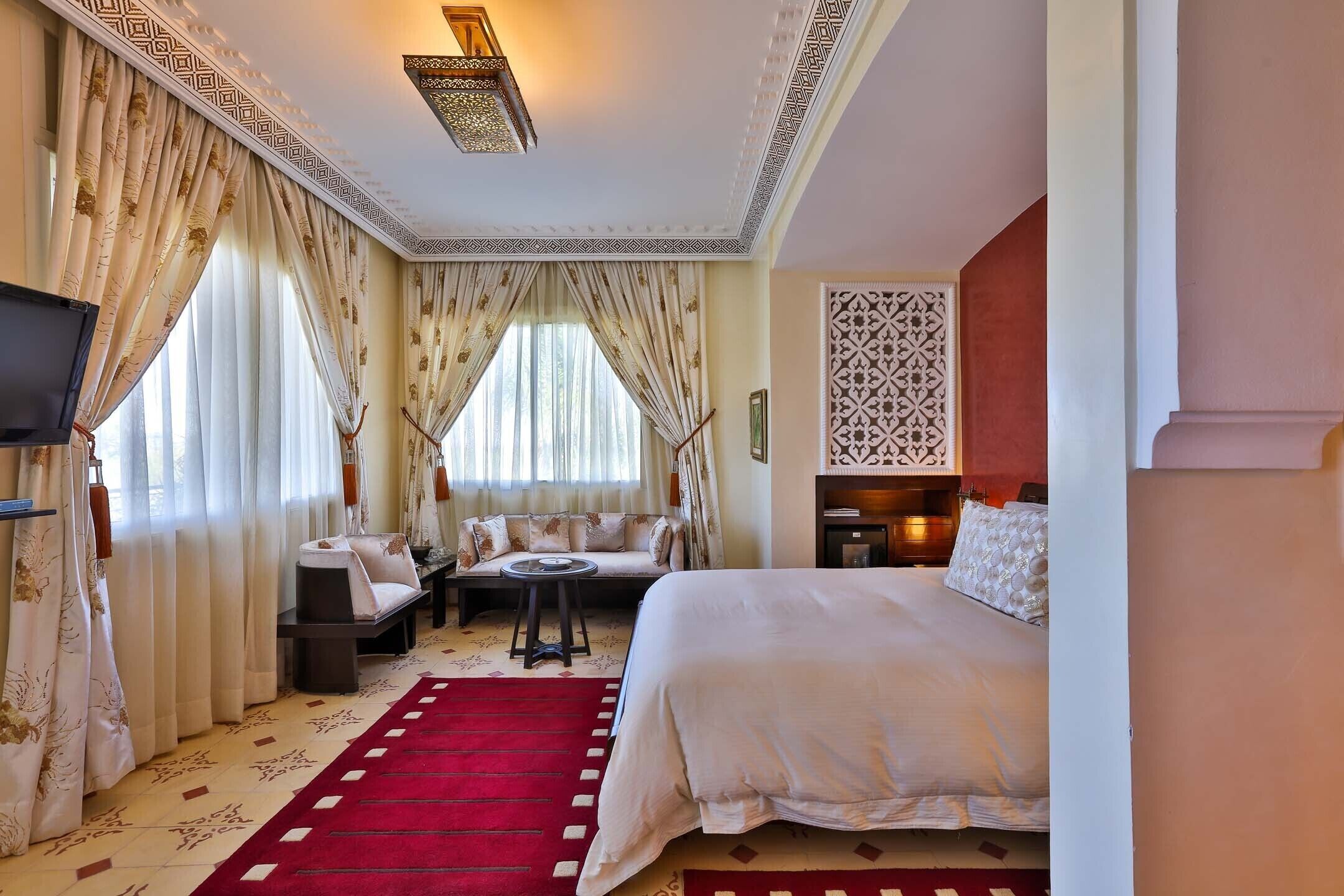 A hotel room with a large bed, a sofa, a small table, and a TV.