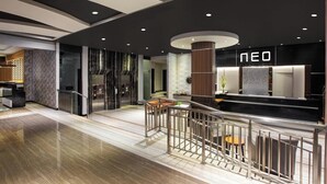 Un moderno vestíbulo de hotel con mostrador de recepción, una escalera y vista del interior.