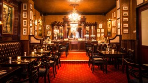 Une salle à manger élégante, avec un tapis rouge, des meubles en bois et un lustre.