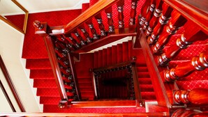 Un magnifique escalier avec des marches recouvertes de moquette rouge et des balustrades en bois.