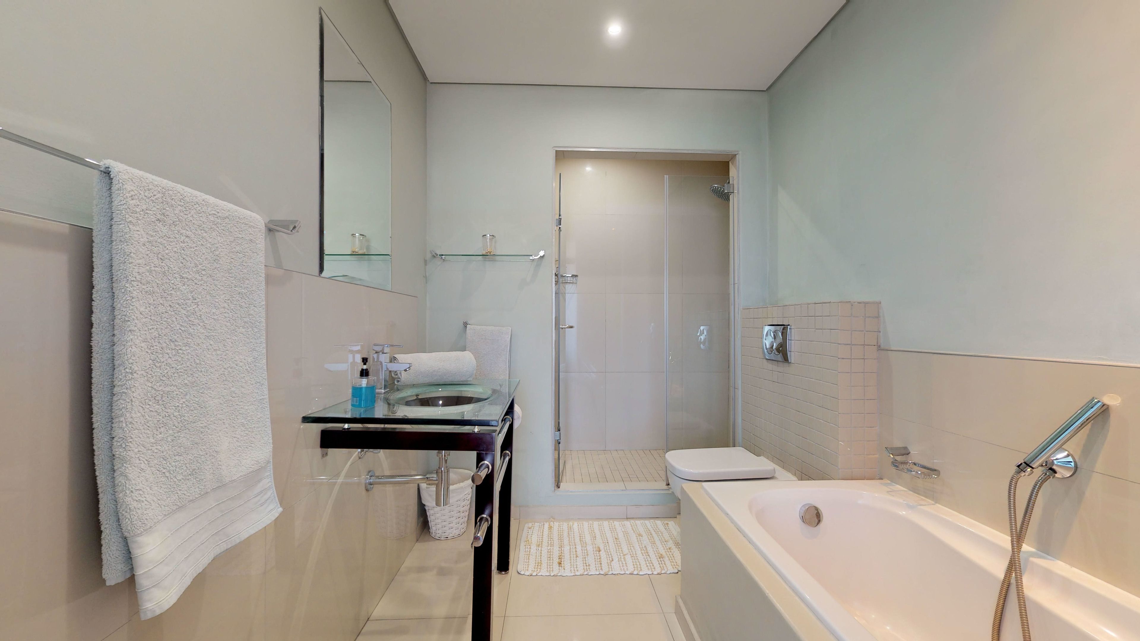 A modern bathroom with a glass shower enclosure, a bathtub, and a toilet.