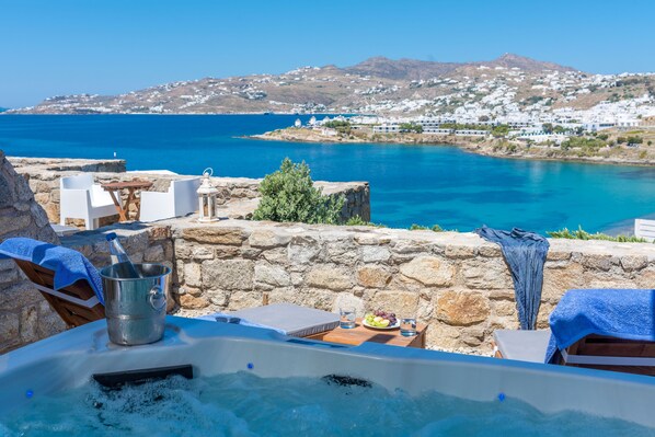 A stone wall with a view of a coastal town and a clear blue sea. - Cape Mykonos (Mykonos)