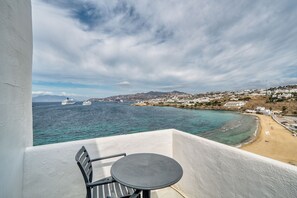A balcony with a table and chair overlooking a coastal town and the sea. - Cape Mykonos (Mykonos)