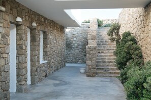 A stone courtyard with a white door, a white pot, and a small tree. - Cape Mykonos (Mykonos)