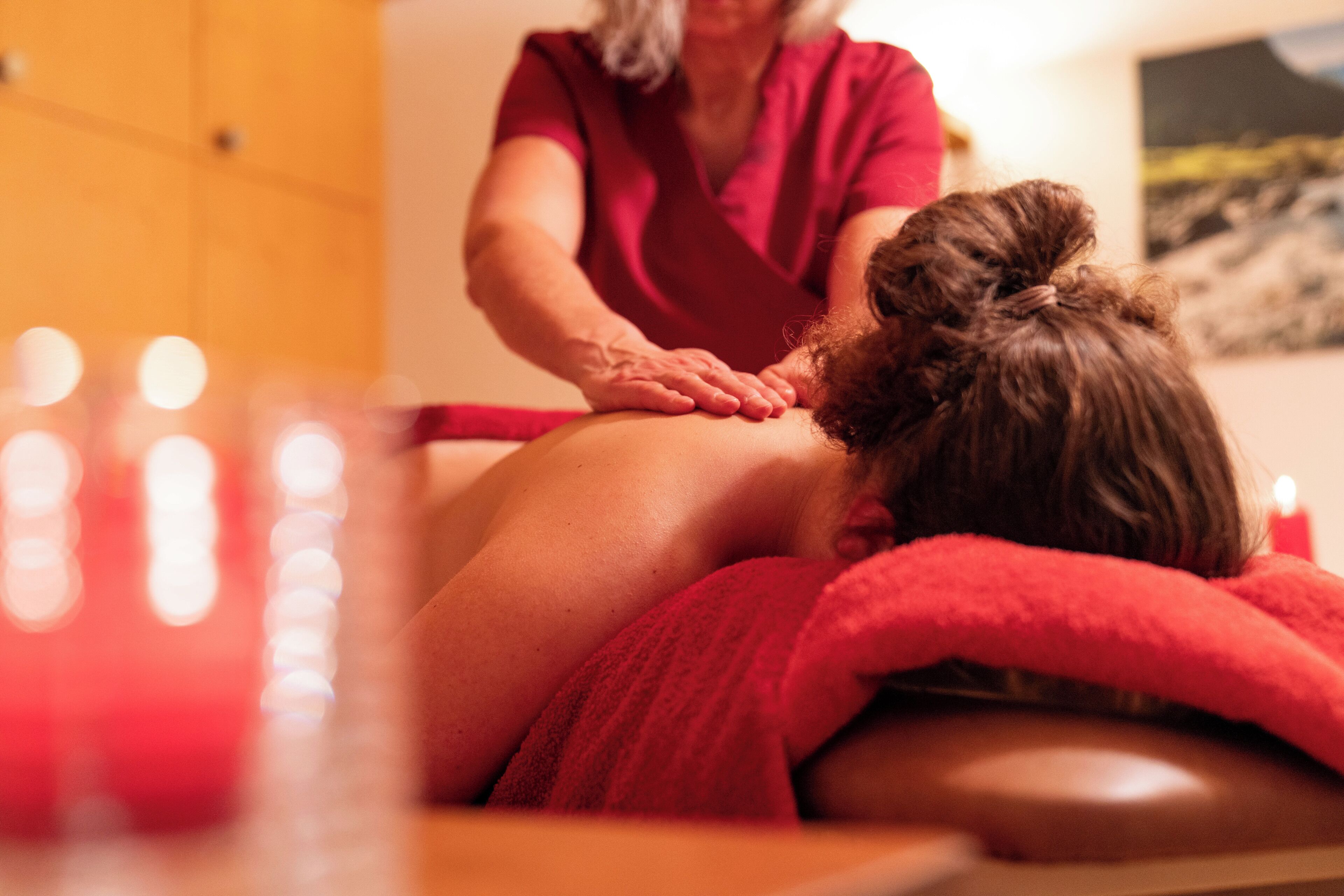 Een massagebehandeling in een ruimte met houten wanden en een schilderij.