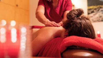 Een massagebehandeling in een ruimte met houten wanden en een schilderij.