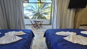 A hotel room with two beds, a balcony with a table and chairs, and a view of palm trees. - Pousada Ceará Porto das Dunas (Aquiraz)