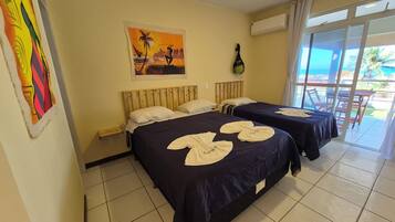 Habitación de hotel con dos camas, un cuadro, un equipo de aire acondicionado y vistas al exterior.