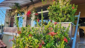 A building with a balcony, surrounded by lush green plants and red flowers. - Pousada Ceará Porto das Dunas (Aquiraz)