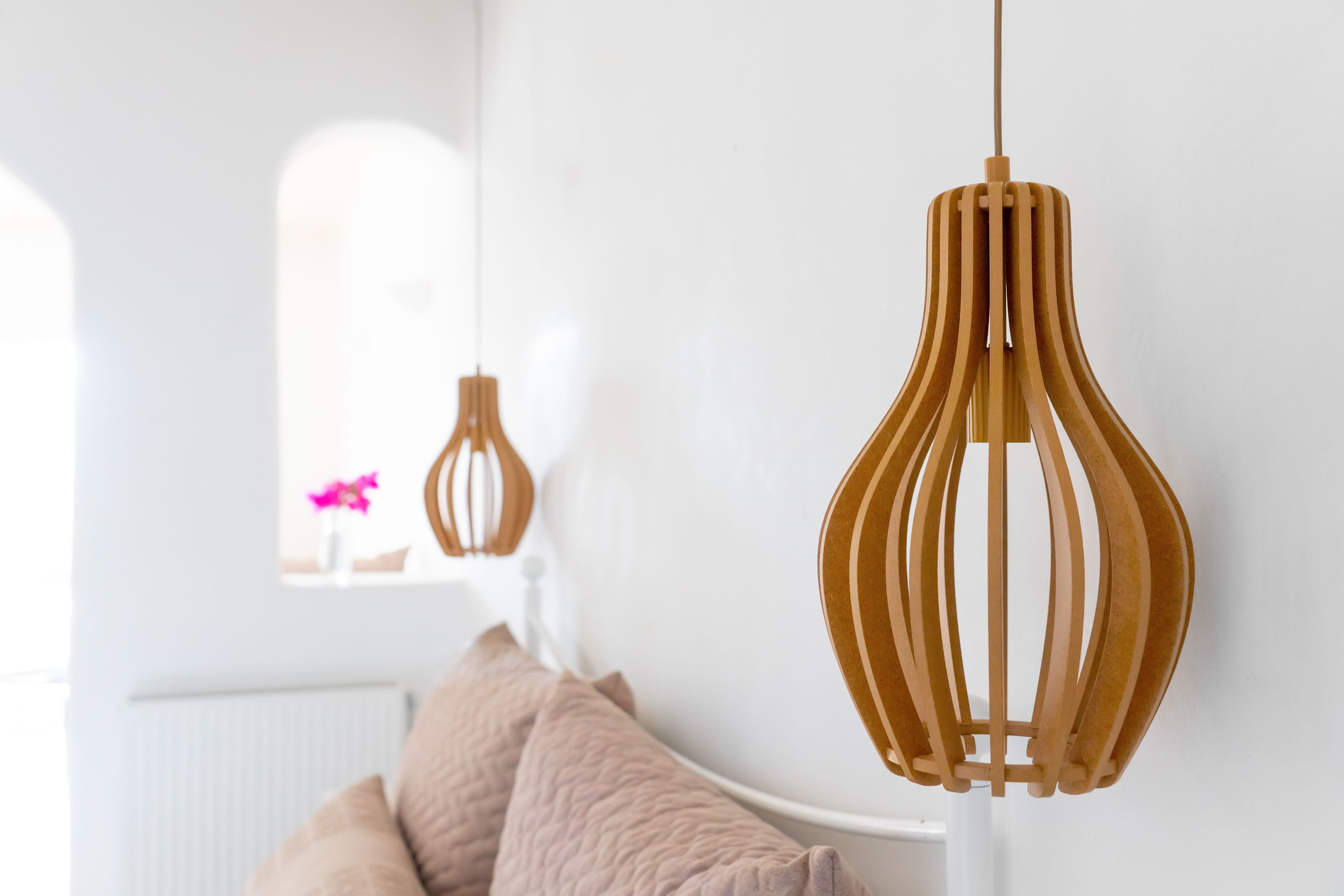 A modern interior with a white radiator, a beige sofa, and a wooden pendant light.