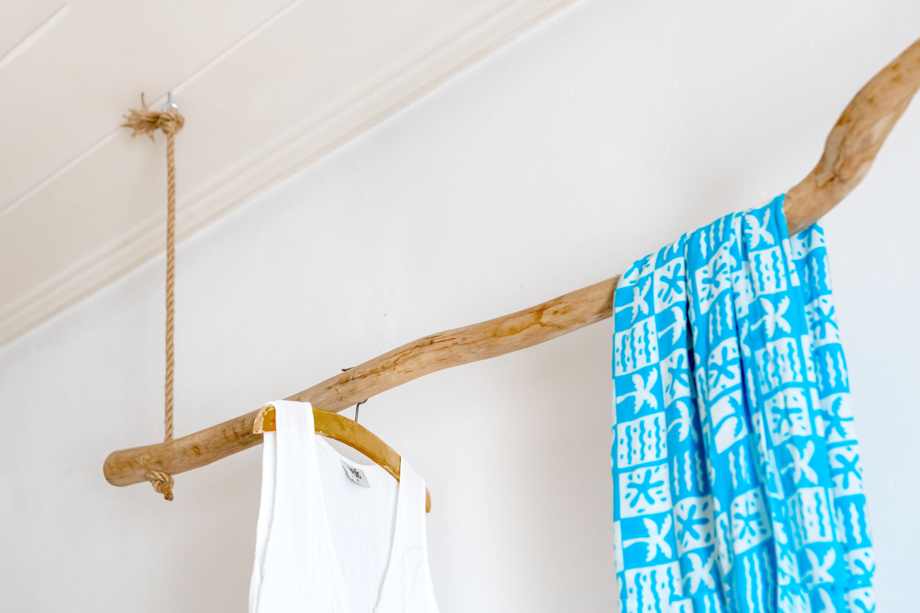 A wooden rack with a white shirt and a blue patterned garment hanging.