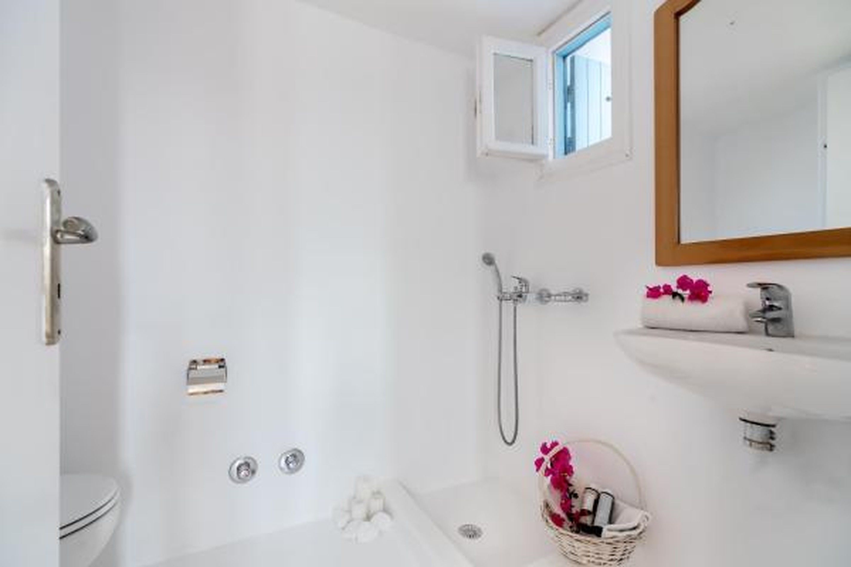 A bathroom with a shower, toilet, and a sink with a mirror.