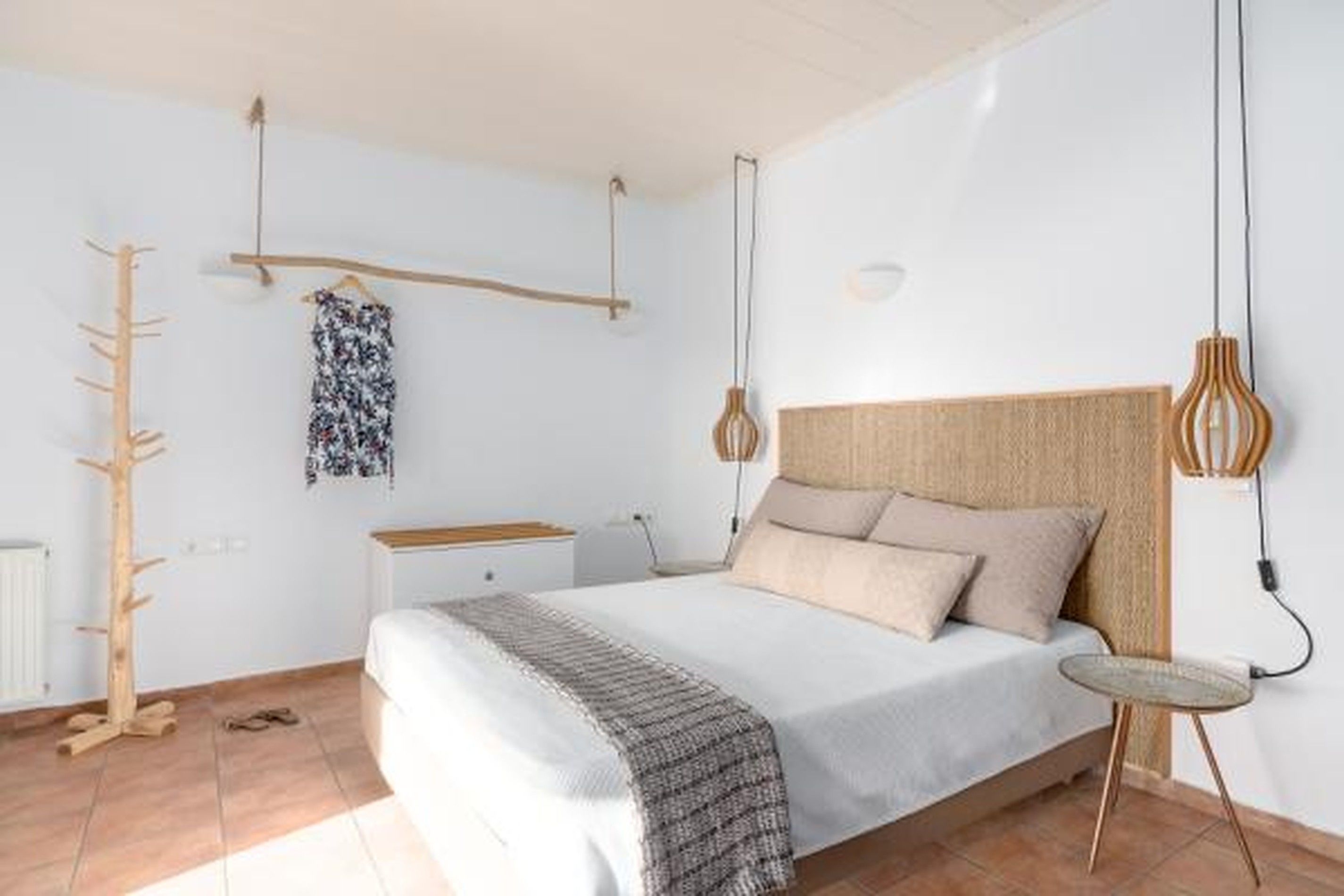A bedroom with a bed, bedside table, lamp, and a coat rack.