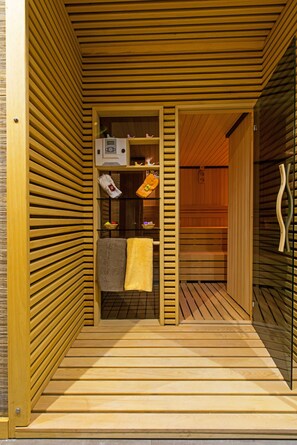 A sauna room with wooden slats, a bench, a towel, and a small shelf with items. - Hotel Favori (Istanbul)