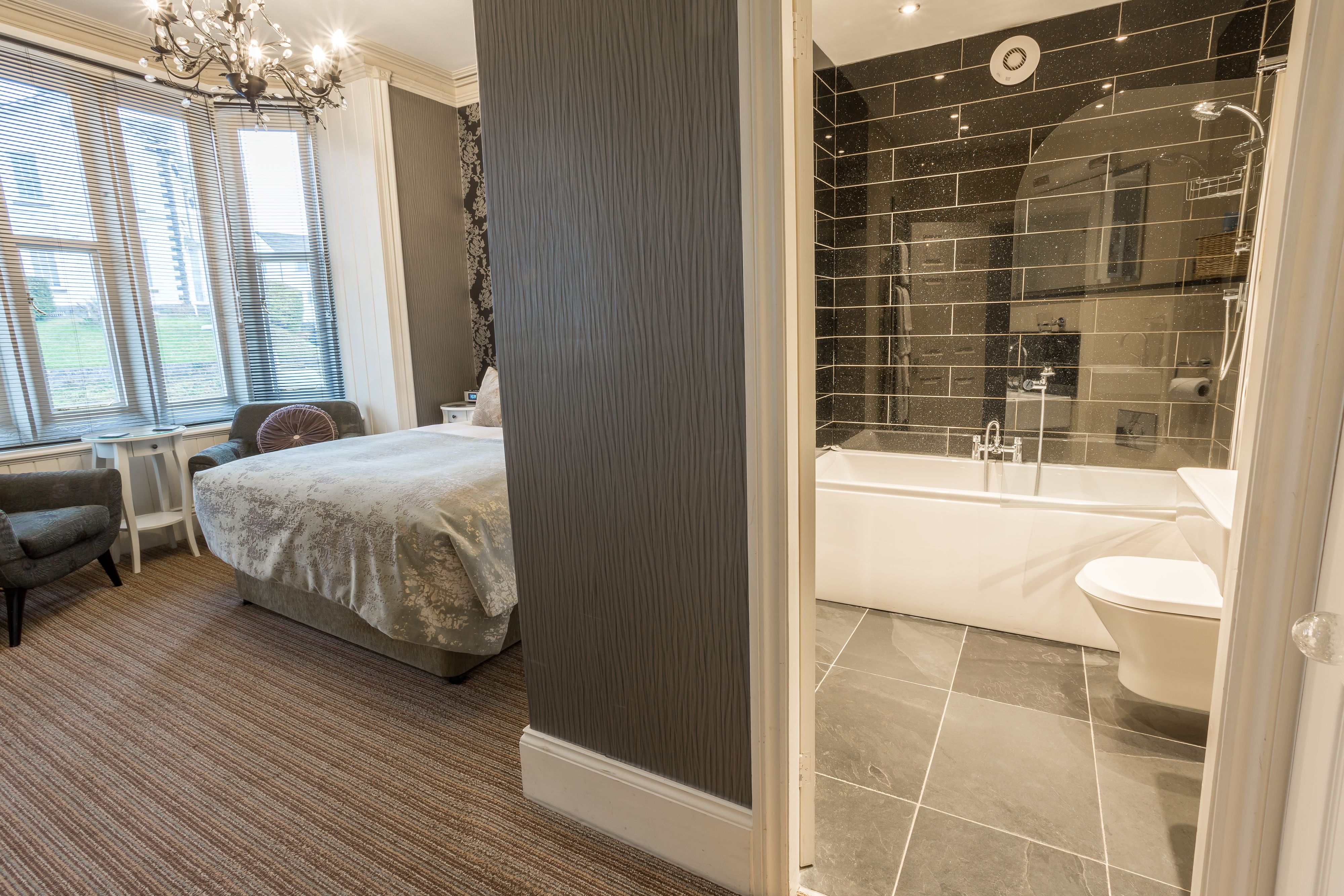 Quarto moderno com uma cama grande, um espaço de estar e vista para o exterior.