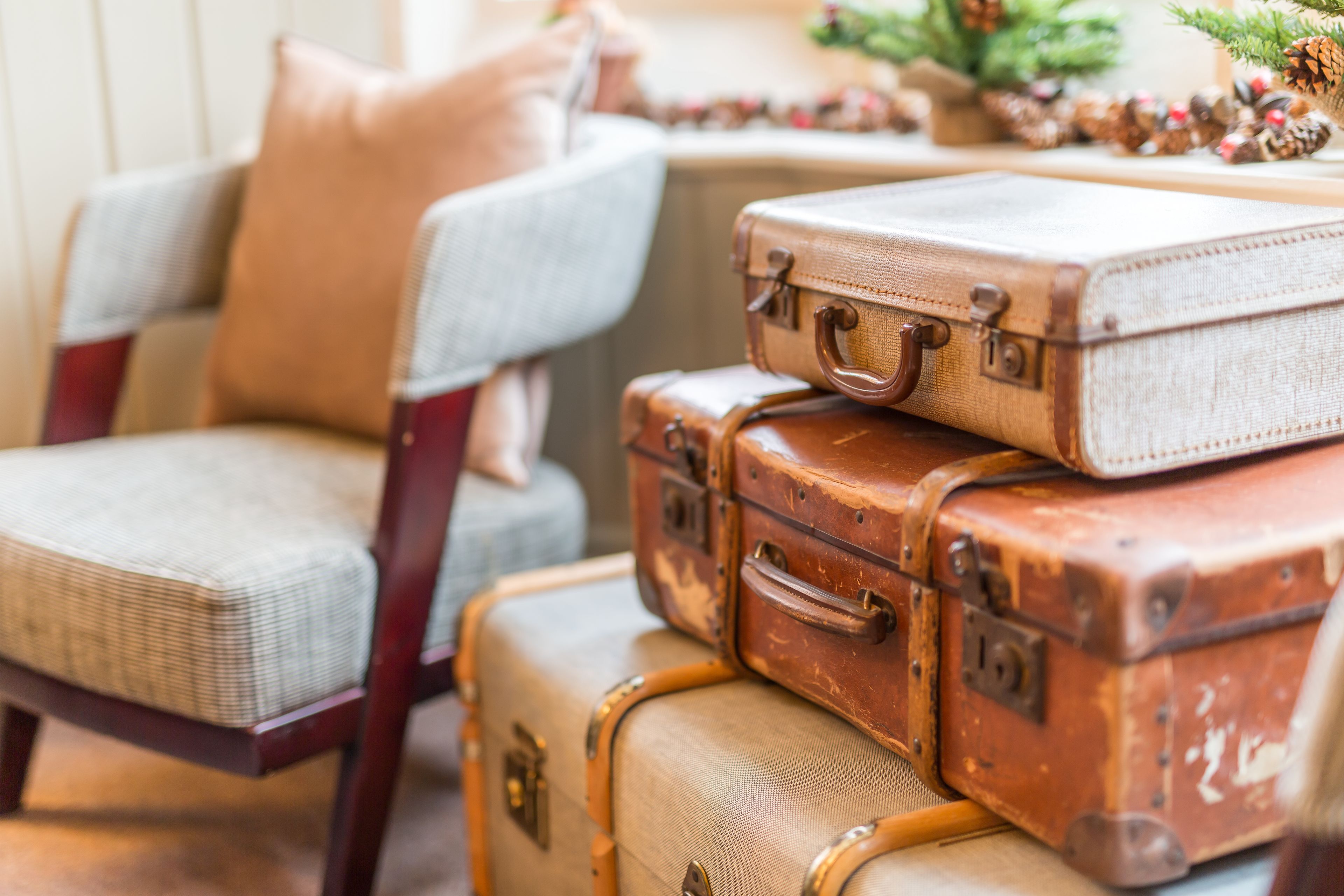 A stack of vintage suitcases on a wooden chair.