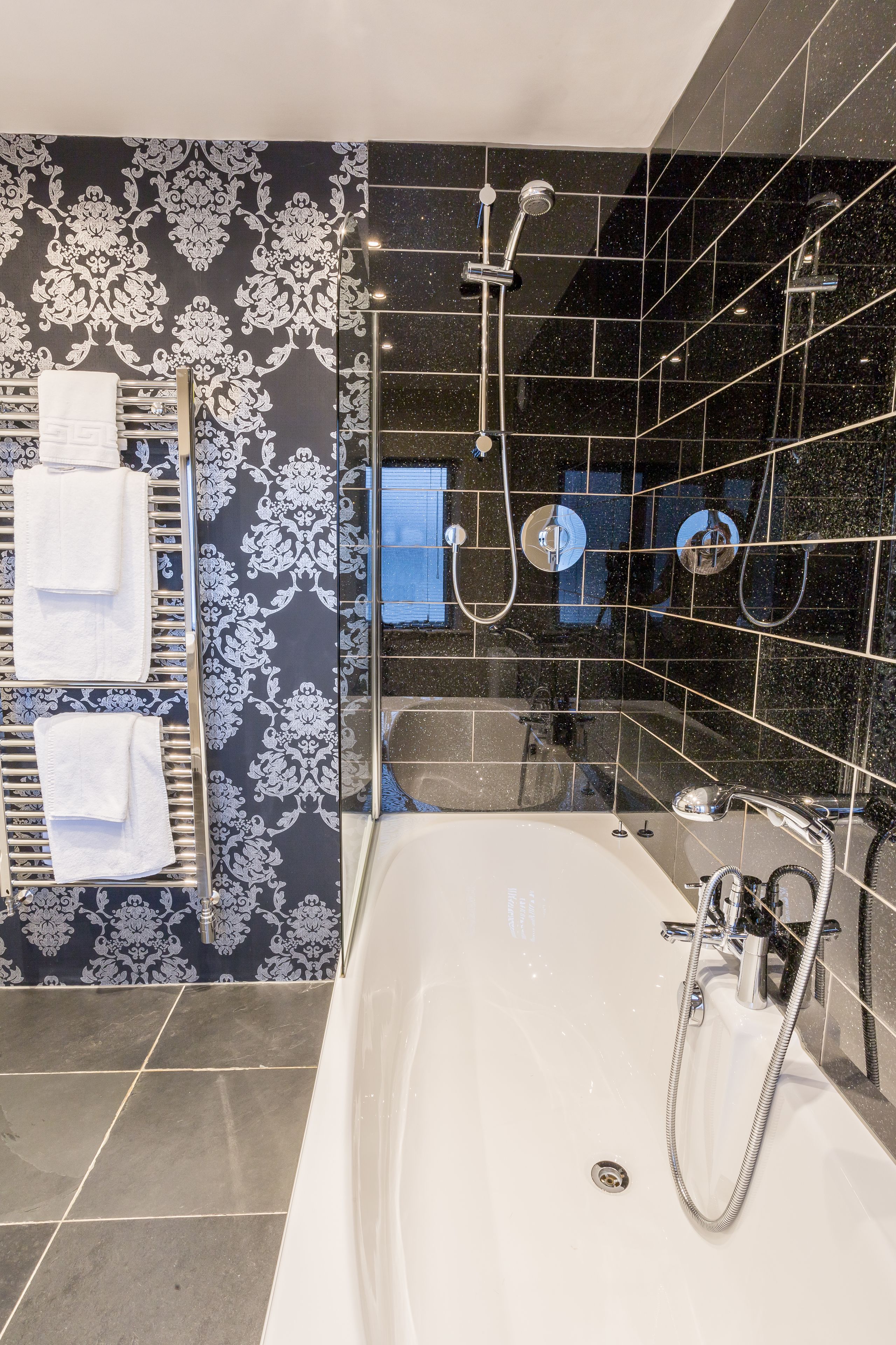 A modern bathroom with a large bathtub, a shower area, and a towel rack with towels.
