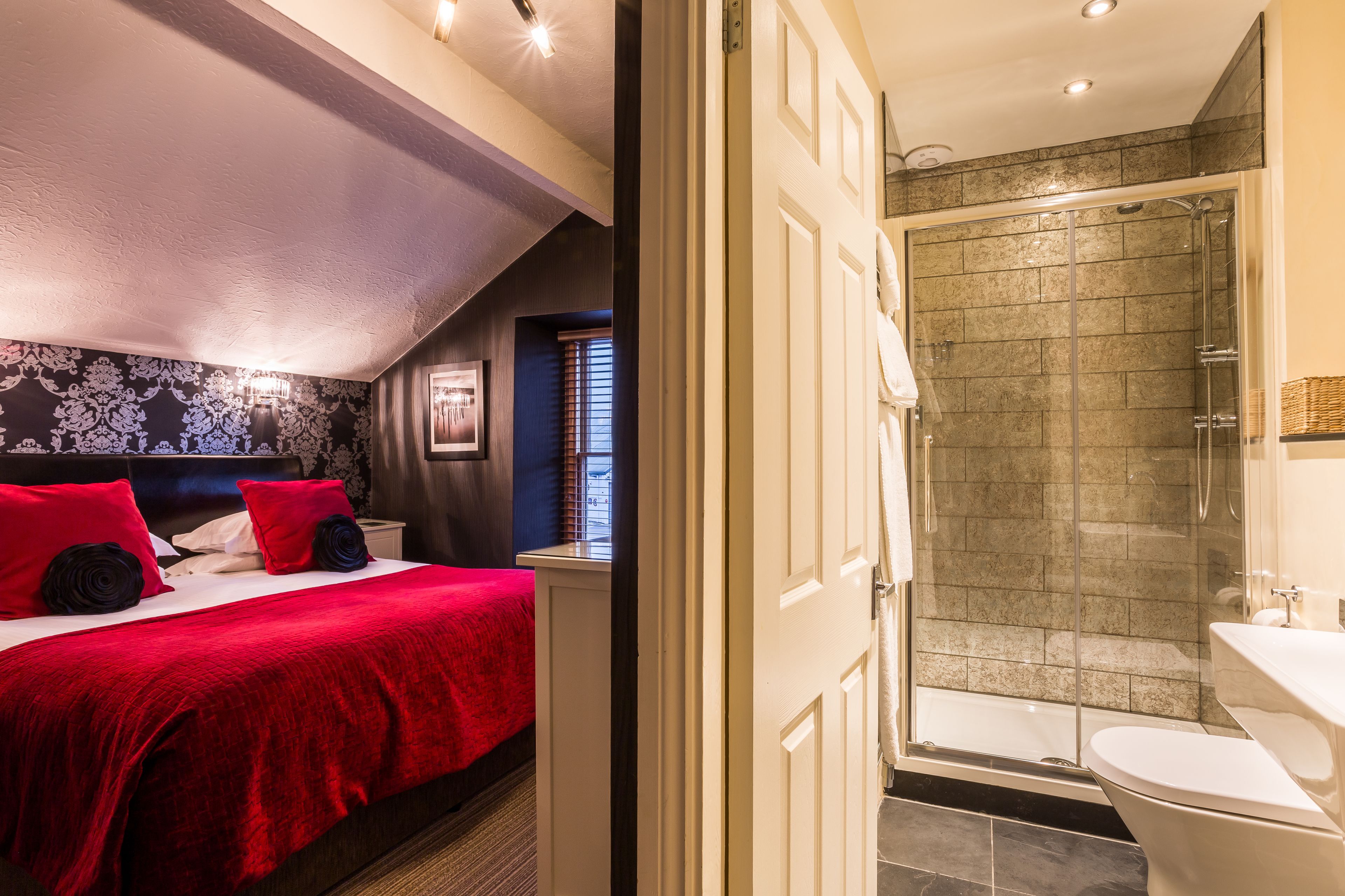 A hotel room with a large bed, a shower area, and a bathroom.